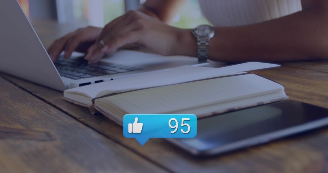 Typing on Laptop with Notebook and Tablet Showing 95 Social Like Notification Bubble