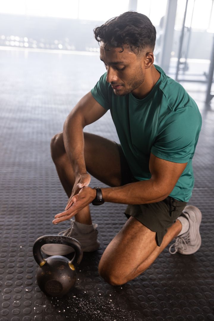 Man Kneeling in Gym Training with Kettlebell Chalk Preparation