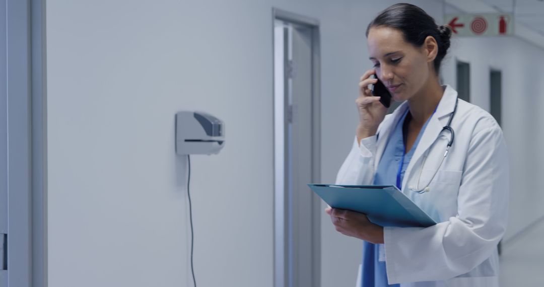 Female Doctor Discussing Patient Case by Phone in Hospital Corridor - Free Images, Stock Photos and Pictures on Pikwizard.com