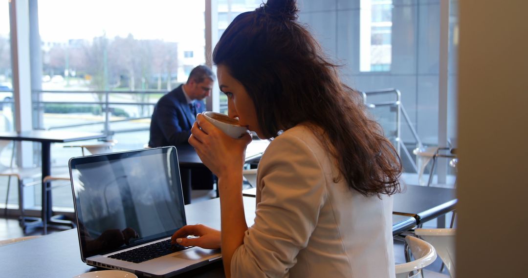 Woman Working on Laptop in Modern Cafe While Drinking Coffee - Free Images, Stock Photos and Pictures on Pikwizard.com