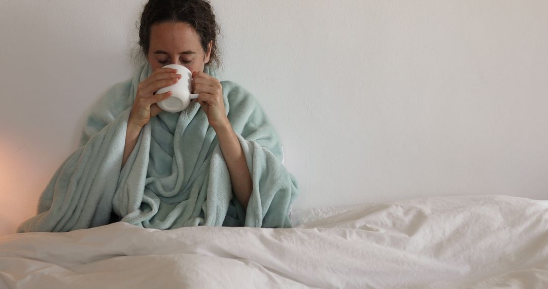 Woman Wrapped in Blanket Drinking Hot Beverage in Bed - Free Images, Stock Photos and Pictures on Pikwizard.com