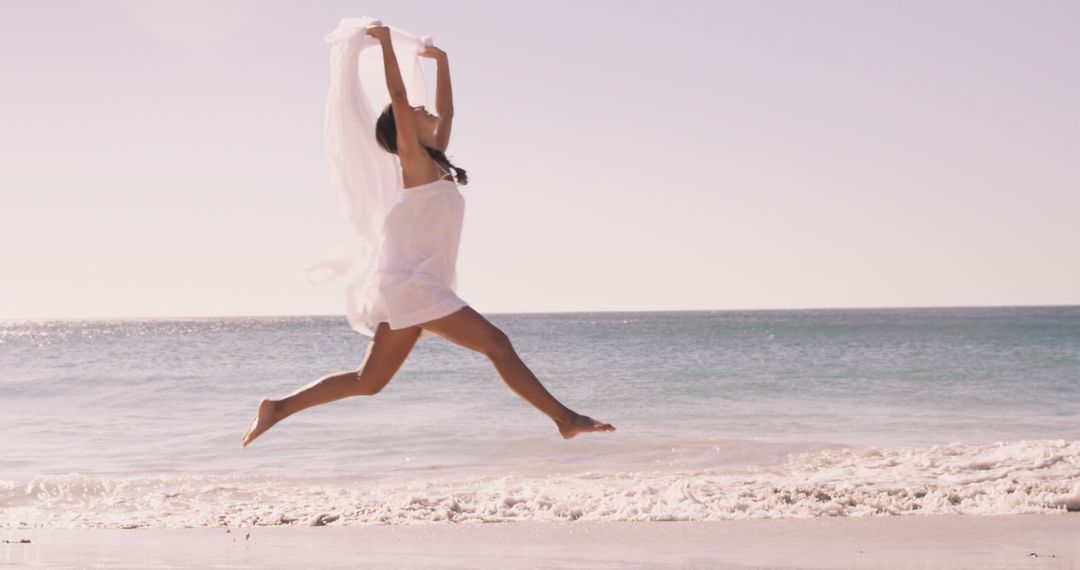 Woman Leaping with Fabric on Sunny Beach - Free Images, Stock Photos and Pictures on Pikwizard.com