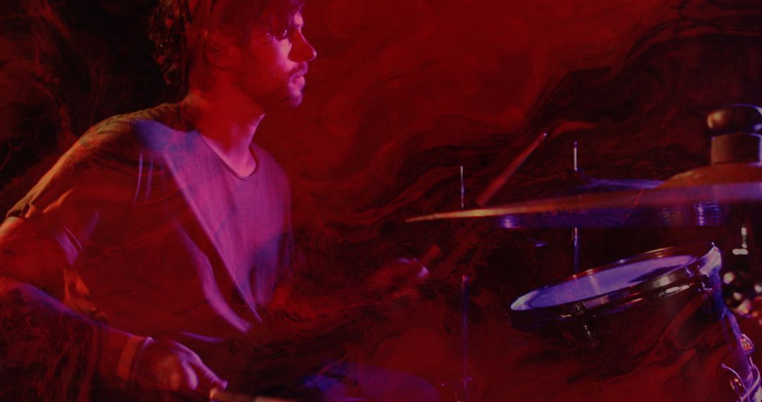 Caucasian Drummer Performing with Vibrant Red Lighting