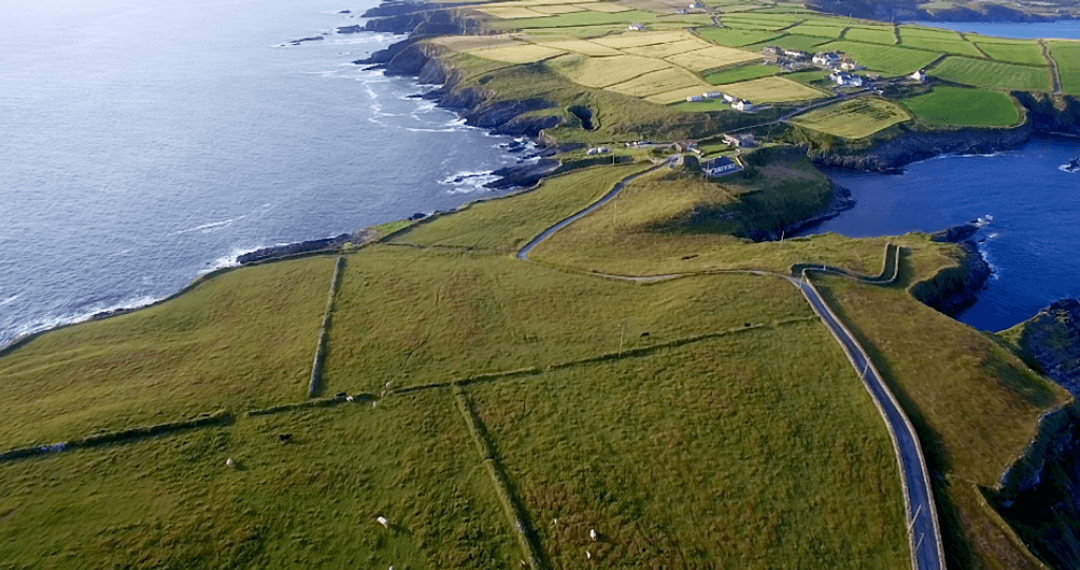 Aerial View Capturing Rugged Coastal and Lush Fields Panorama