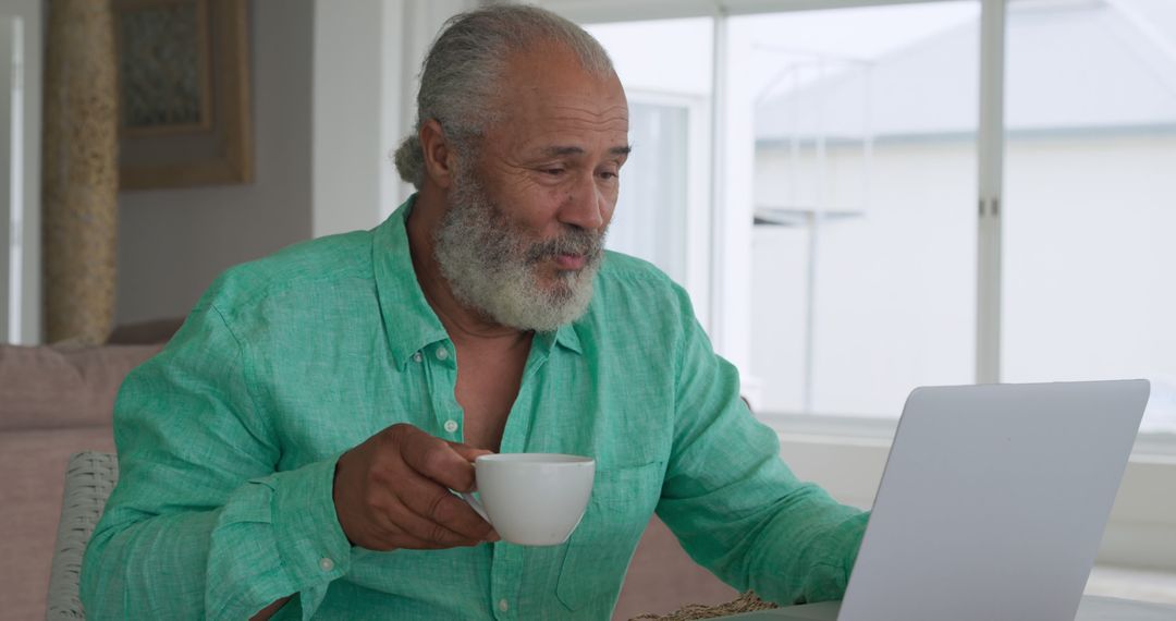 Senior Man Drinking Coffee While Using Laptop at Home - Free Images, Stock Photos and Pictures on Pikwizard.com