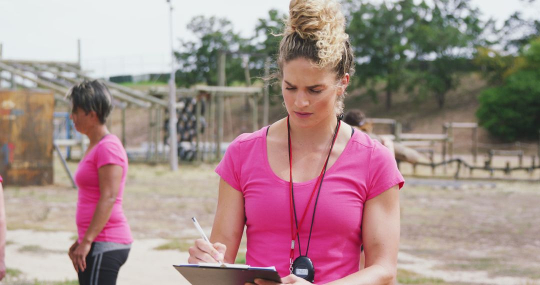 Female Instructor Taking Notes During Outdoor Training Session - Free Images, Stock Photos and Pictures on Pikwizard.com