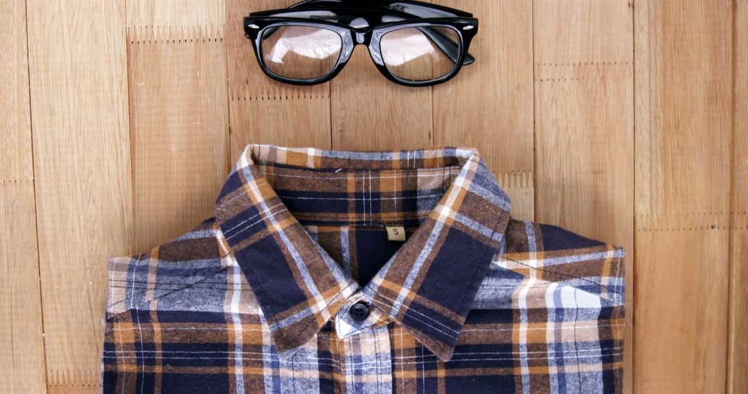 Folded Checkered Shirt with Black Glasses on Wooden Surface - Free Images, Stock Photos and Pictures on Pikwizard.com