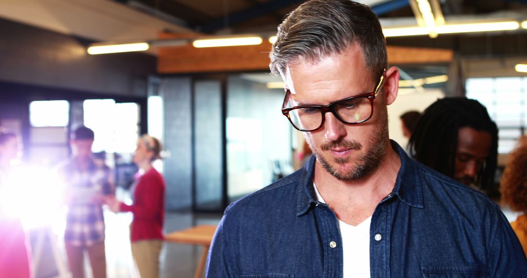 Focused man in modern office space wearing glasses and casual attire - Free Images, Stock Photos and Pictures on Pikwizard.com