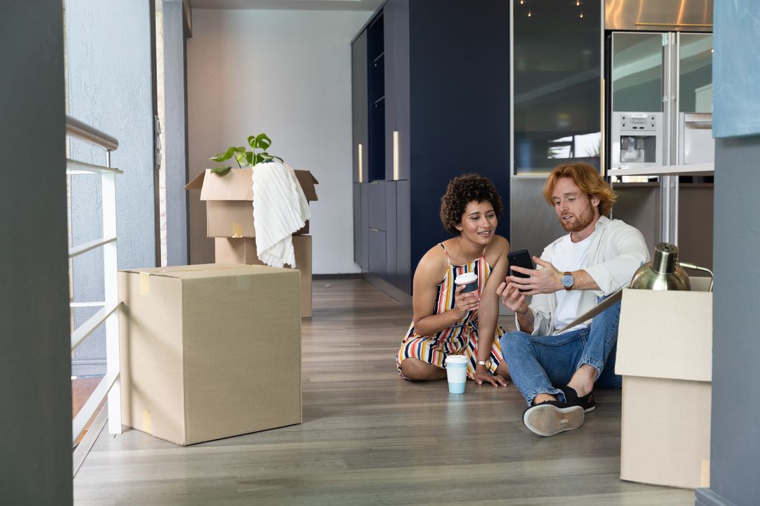 Diverse Couple Relaxing with Smartphone During Unpacking