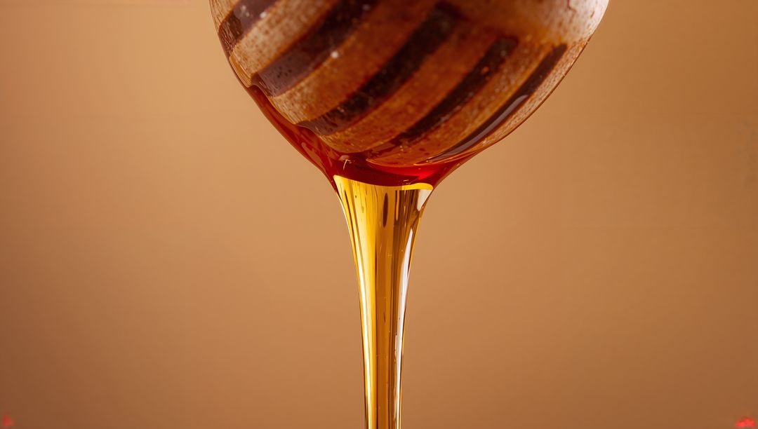 Amber Honey Pouring from Grooved Wooden Dipper Closeup Dripping Viscous Stream