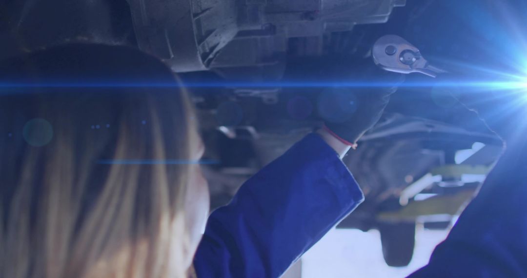 Gloved Mechanic Using Socket Wrench Under Car Inspection