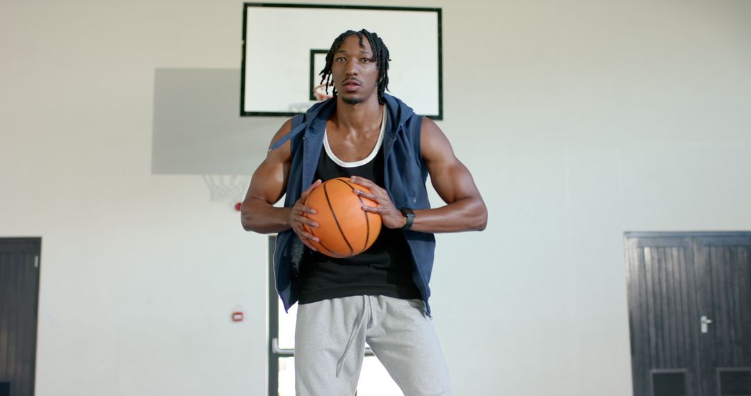 Focused Basketball Player Holding Ball in Gym Environment