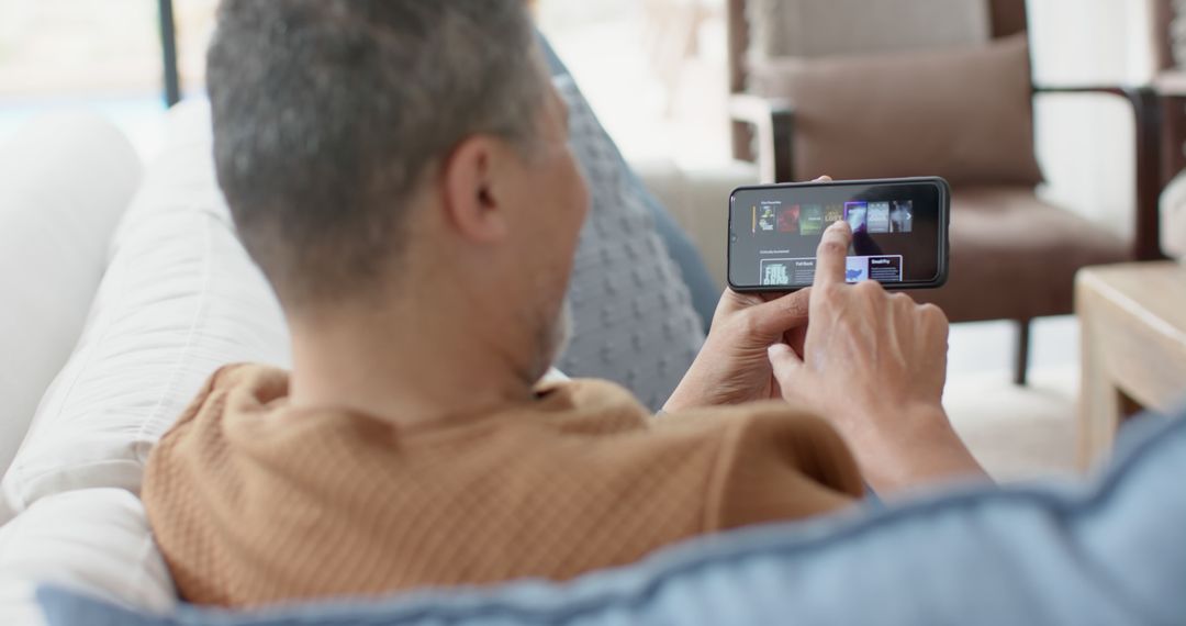 Man Relaxing on Sofa Using Smartphone Watching Videos - Free Images, Stock Photos and Pictures on Pikwizard.com