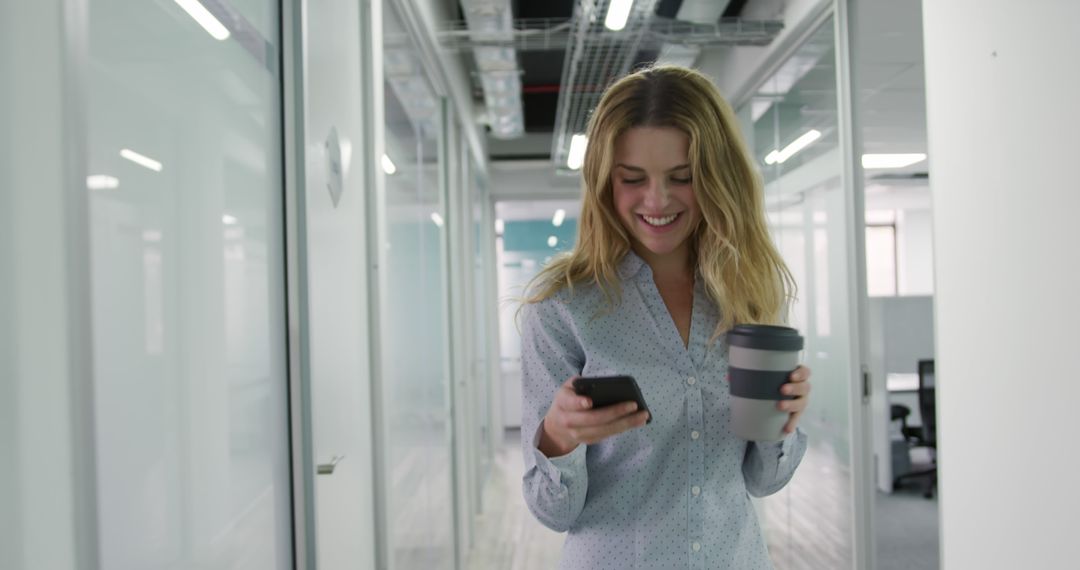 Smiling Businesswoman Holding Coffee Cup and Smartphone in Office Hall - Free Images, Stock Photos and Pictures on Pikwizard.com