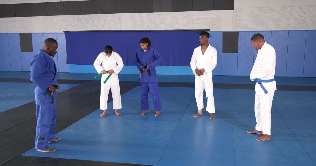 Martial Arts Practitioners Adjusting Belts In Dojo