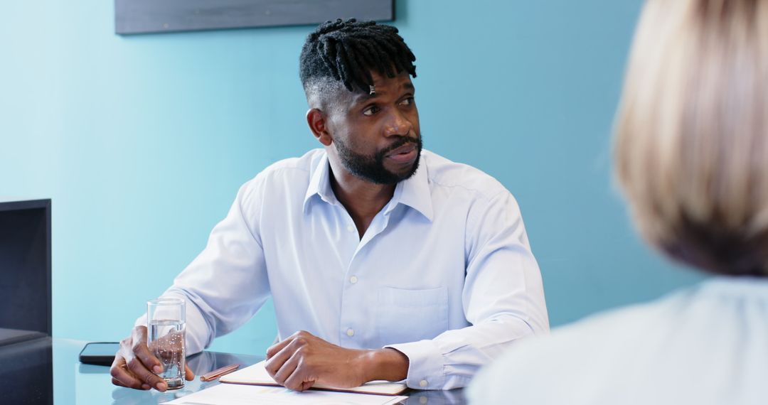 Businessman Engaging in Office Meeting, Emphasizing Teamwork and Hydration
