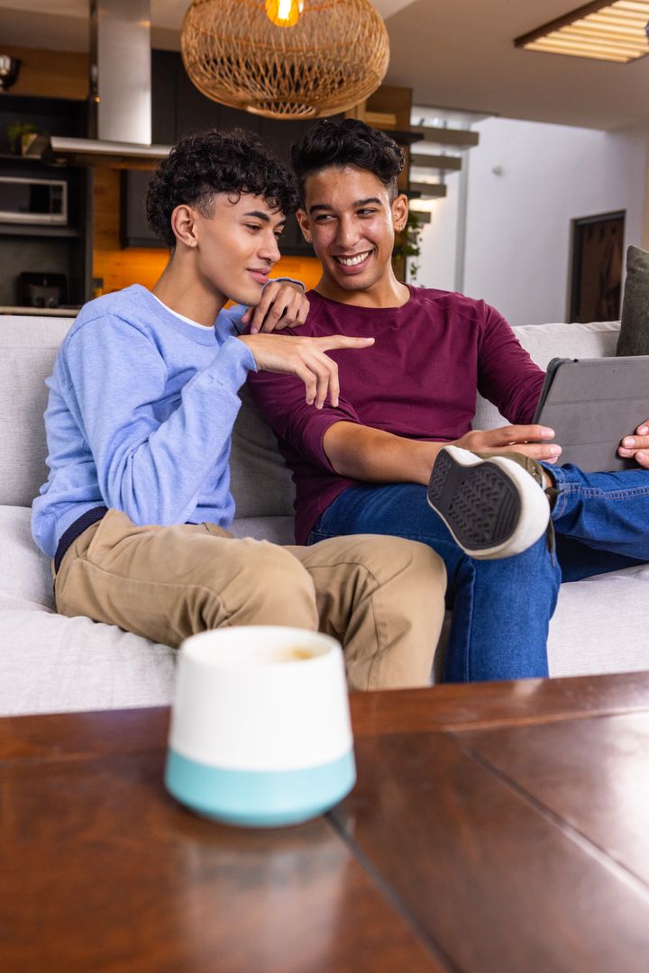 Friends Using Tablet on Sofa with Smart Speaker Nearby