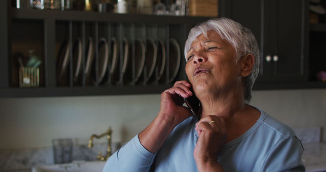 Senior Woman Conversing on Phone in Kitchen Raising Hand Expressively - Free Images, Stock Photos and Pictures on Pikwizard.com