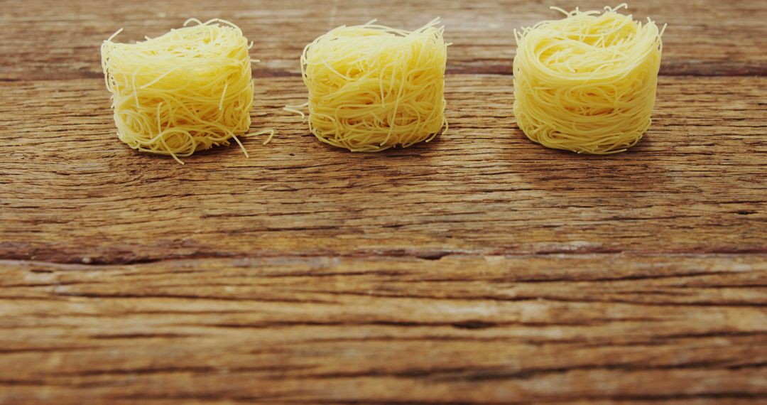 Three Nests of Dry Pasta on Rustic Wooden Table - Free Images, Stock Photos and Pictures on Pikwizard.com