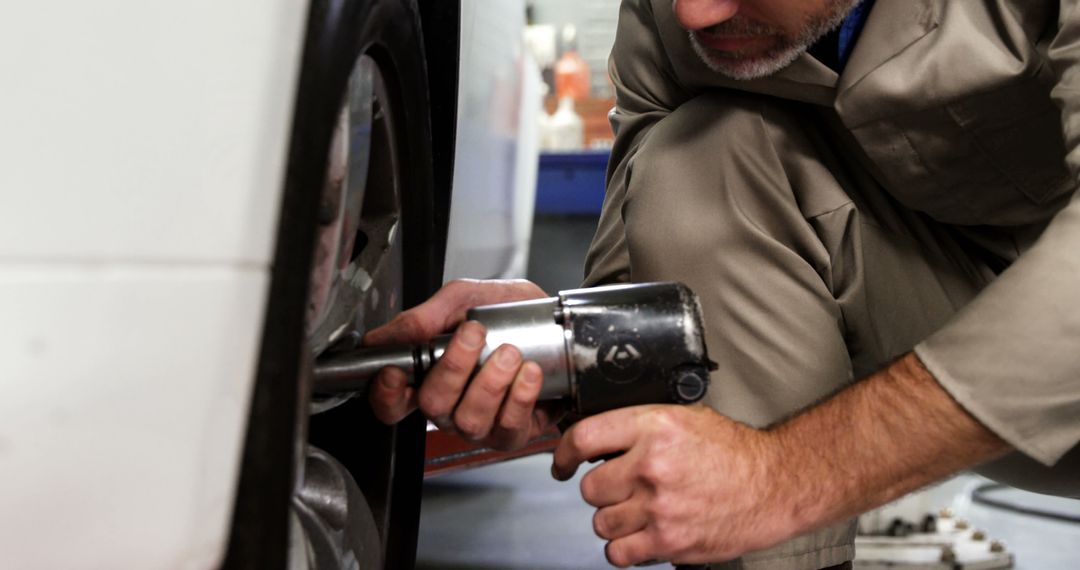 Mechanic Fixing Tire with Impact Wrench in Auto Repair Shop - Free Images, Stock Photos and Pictures on Pikwizard.com