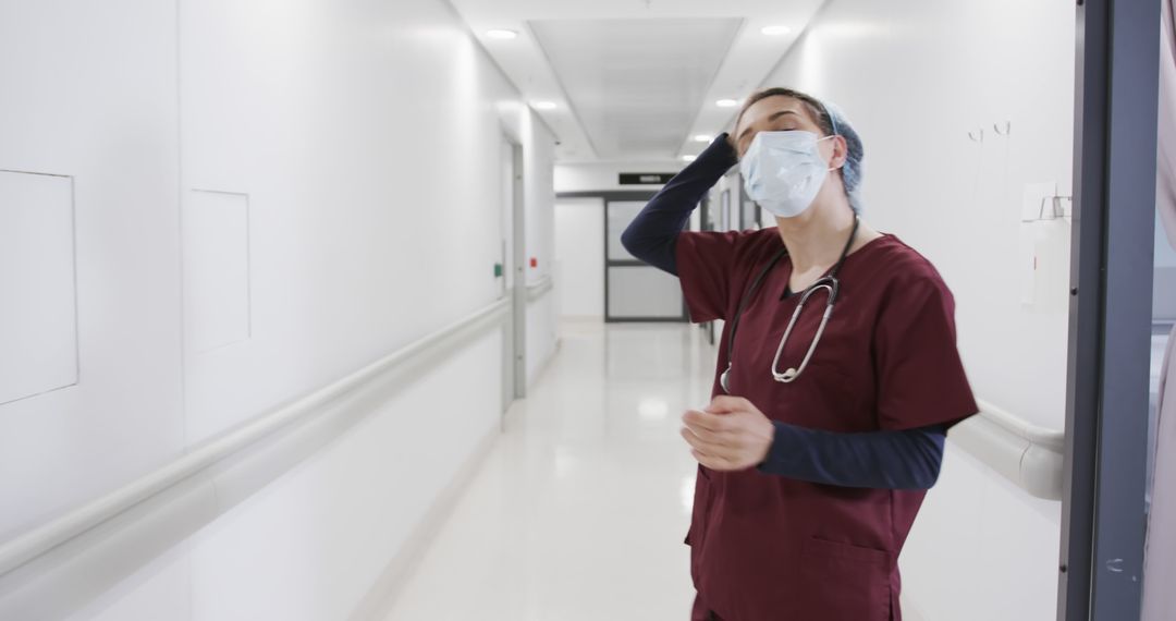 Tired Healthcare Worker in Empty Hospital Corridor - Free Images, Stock Photos and Pictures on Pikwizard.com