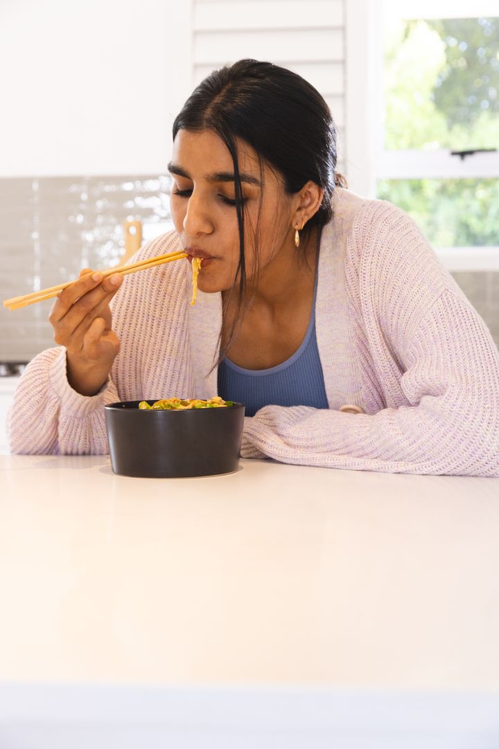 Woman Enjoying Delicious Noodles Using Chopsticks at Home