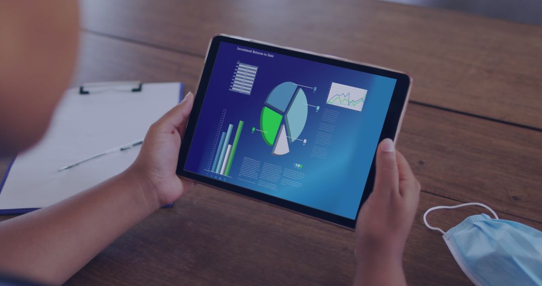 Person Analyzing Business Data on Tablet at Office Desk