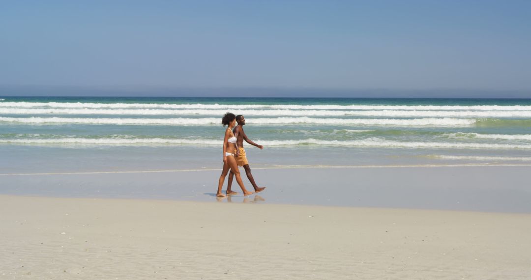 Couple Enjoying Leisurely Beach Walk on Sunny Day - Free Images, Stock Photos and Pictures on Pikwizard.com