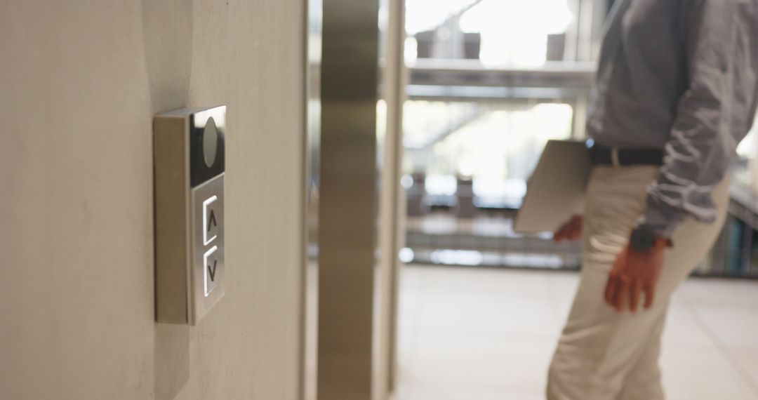Professional Approaching Elevator in Modern Office Corridor