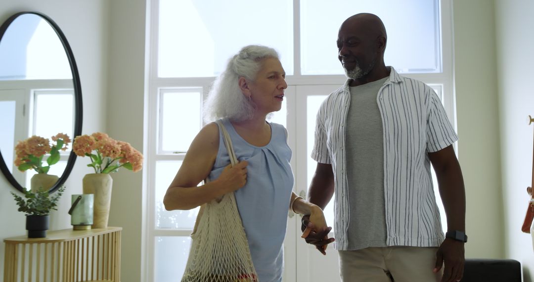 Happy Senior Couple Holding Hands in Bright Entryway