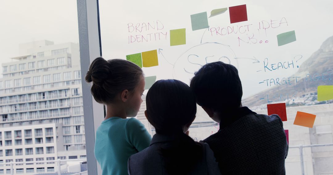 Businesspeople Strategizing Marketing Plan with Notes on Glass Wall - Free Images, Stock Photos and Pictures on Pikwizard.com