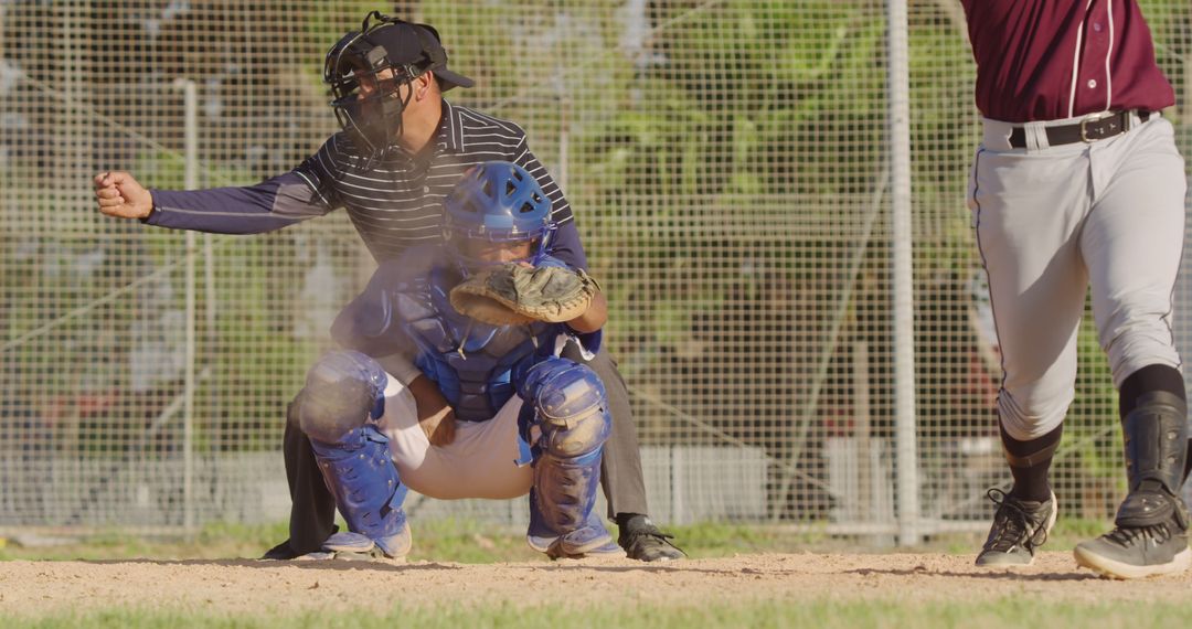 Baseball catcher catching ball during game with umpire making a call - Free Images, Stock Photos and Pictures on Pikwizard.com