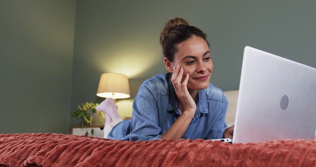 Woman Relaxing on Bed While Using Laptop in Cozy Bedroom