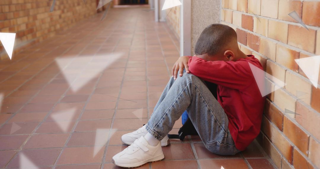 Young Boy Hugging Knees in School Hallway, Coping with Loneliness