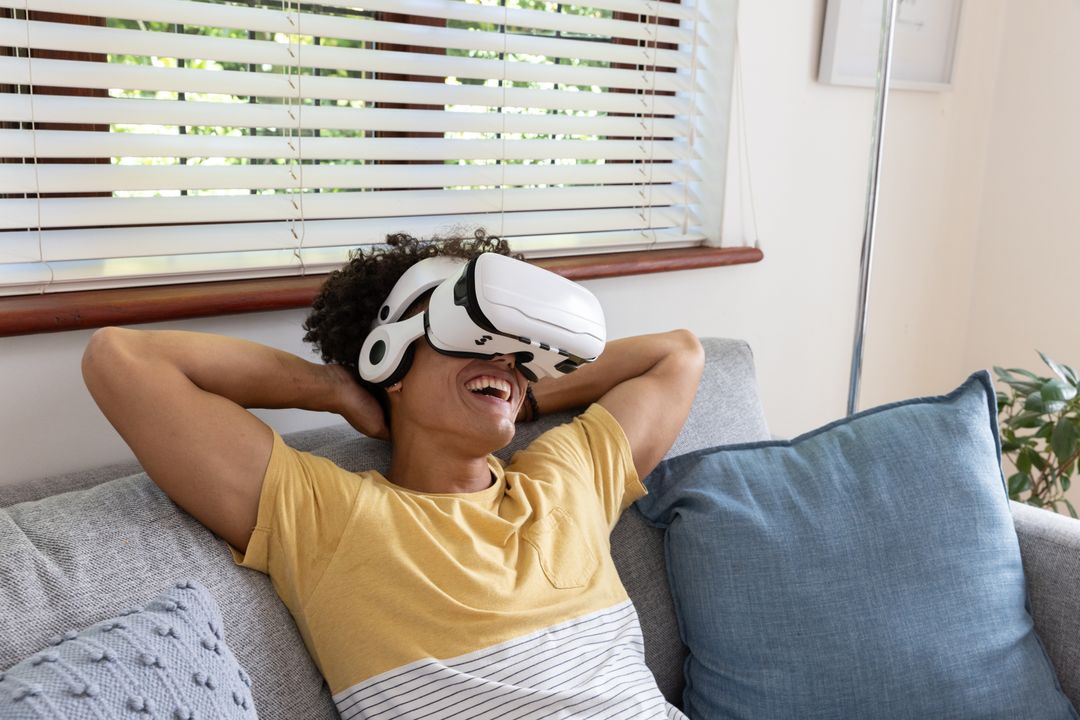 Man Relaxing on Sofa Wearing VR Headset Enjoying Simulated Experience