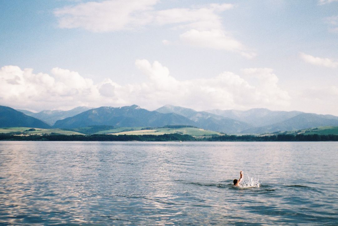Person Swimming in Tranquil Lake with Mountain Background - Free Images, Stock Photos and Pictures on Pikwizard.com