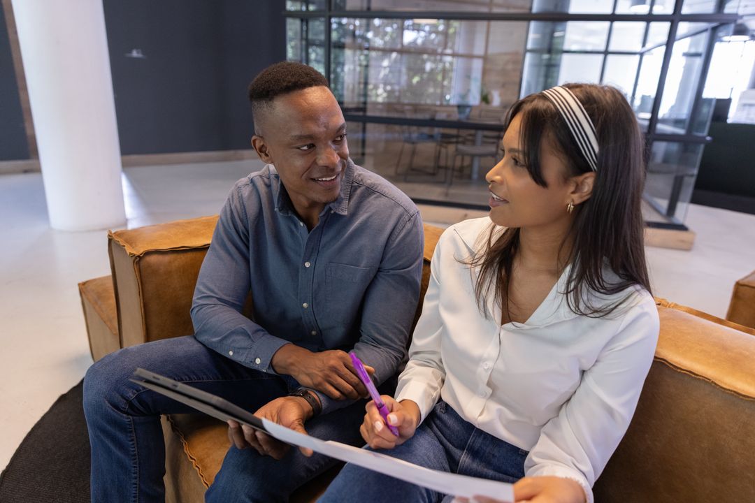 Diverse coworkers collaborating on blueprint in modern office lounge