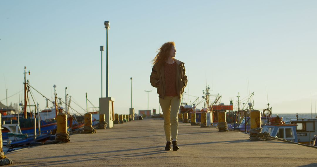 Woman Walking on Dock at Sunset with Fishing Boats in Background - Free Images, Stock Photos and Pictures on Pikwizard.com