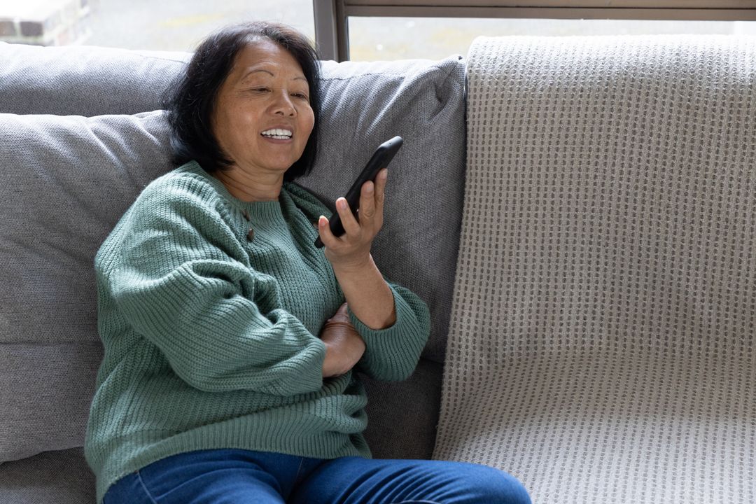 Elderly Woman Using Smartphone on Sofa Relaxed at Home