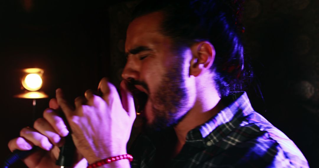 A young Latino man delivers a fervent singing performance under striking stage lights. - Free Images, Stock Photos and Pictures on Pikwizard.com