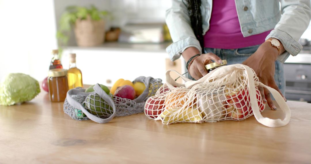 Eco-Friendly Lifestyle: Woman Organizing Produce in Mesh Bags in Kitchen