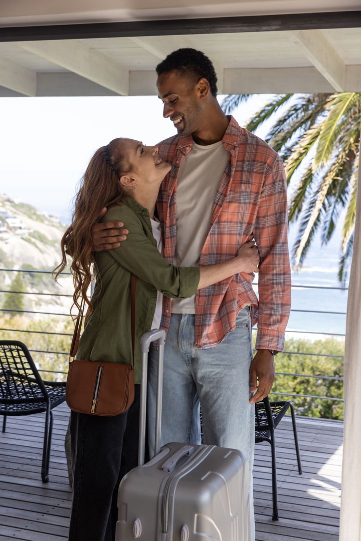 Smiling Couple Embracing on Scenic Ocean View Balcony with Luggage