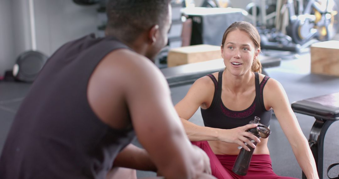 Diverse Gym Pair in Conversation During Matched Workout Routine