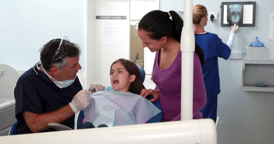 Girl at dental clinic sitting in chair with dentist and her mother - Free Images, Stock Photos and Pictures on Pikwizard.com