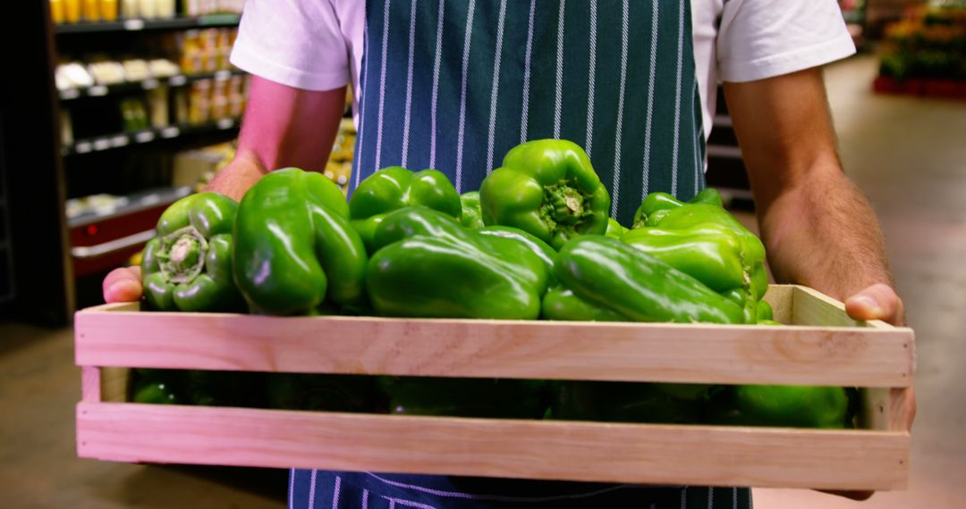 Grocery Worker Carrying Wooden Crate of Fresh Green Bell Peppers in Supermarket - Free Images, Stock Photos and Pictures on Pikwizard.com