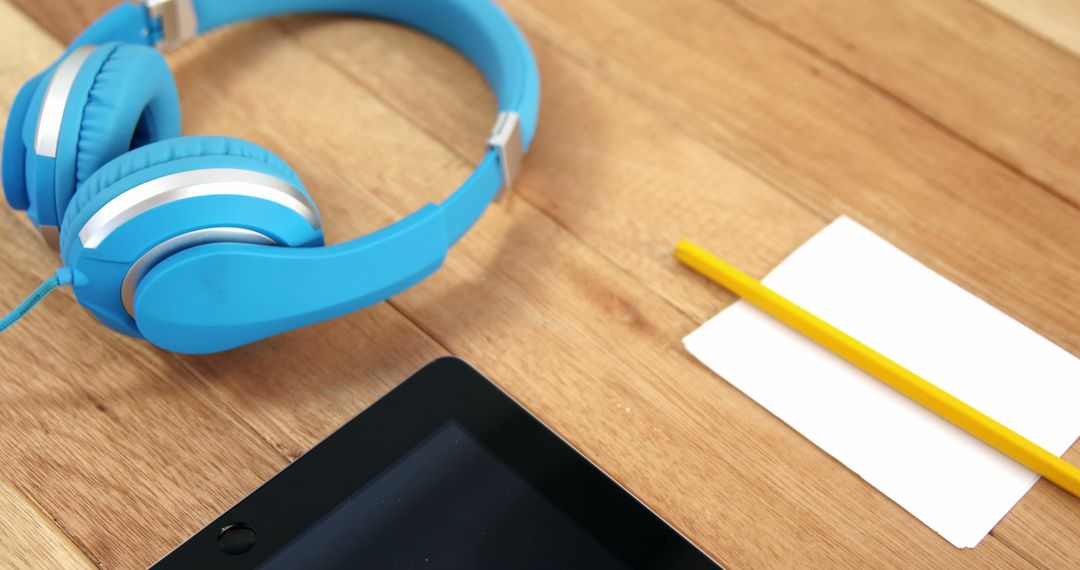 Blue Headphones, Digital Tablet, Pencil, and Paper on Wooden Desk in Modern Workspace - Free Images, Stock Photos and Pictures on Pikwizard.com