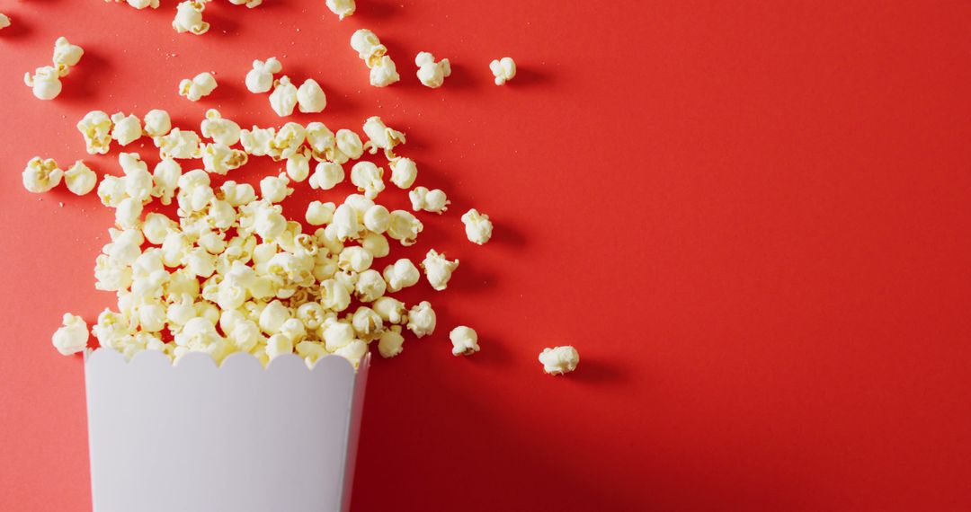 Popcorn Spilling on Vibrant Red Background - Free Images, Stock Photos and Pictures on Pikwizard.com