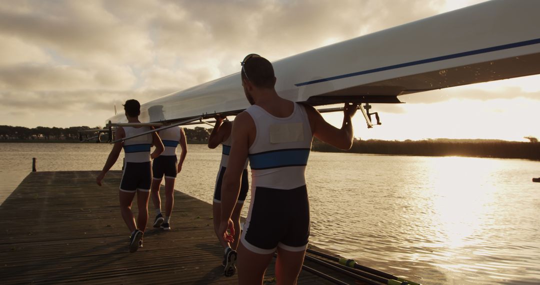 Team of Rowers Carrying Racing Shell at Sunrise Near Waterfront - Free Images, Stock Photos and Pictures on Pikwizard.com