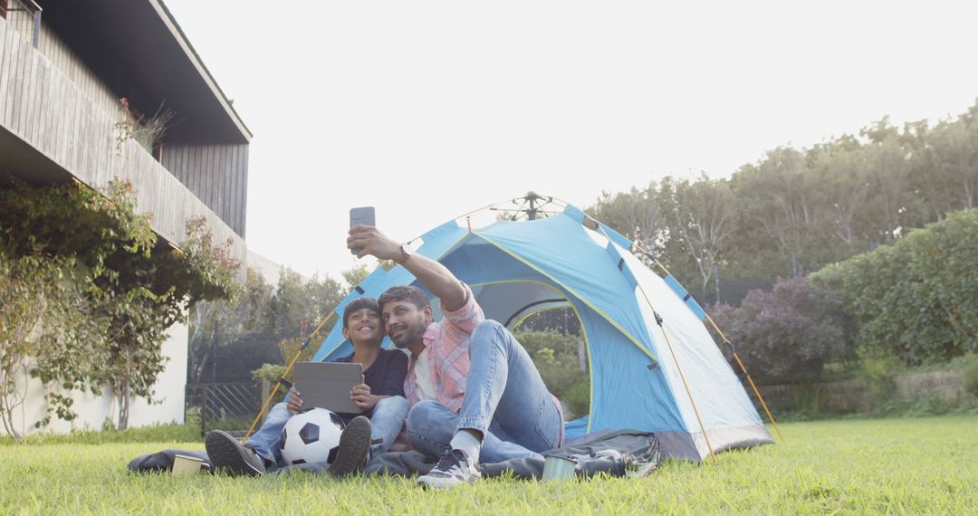 Father Son Taking Selfie Lawn Camping with Tech Gadgets