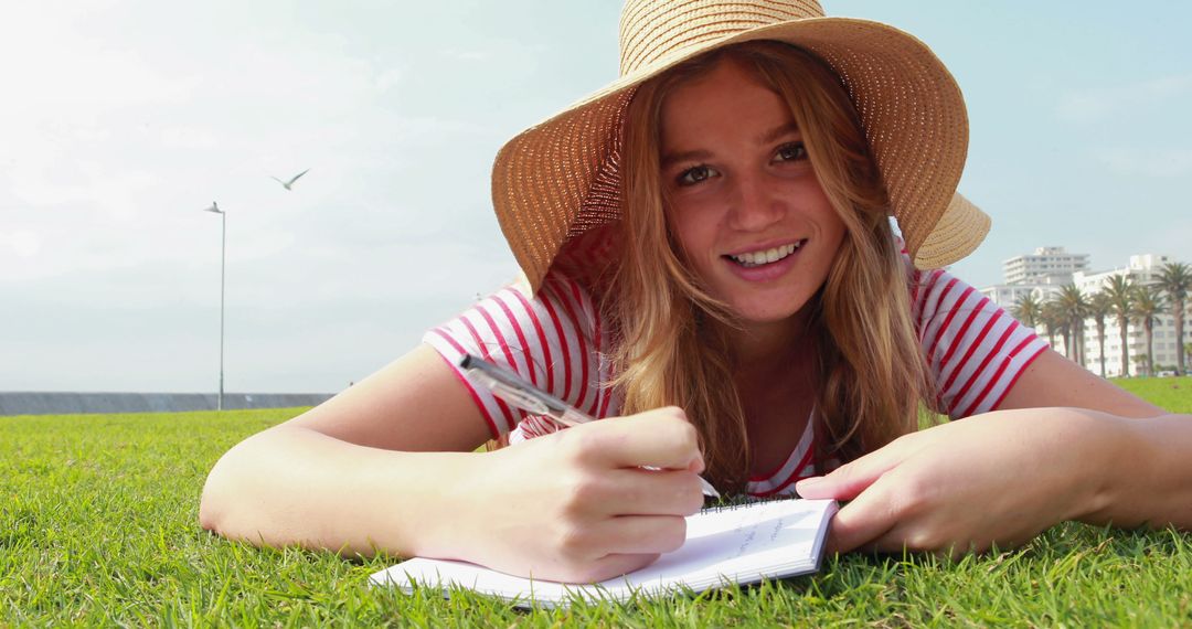 Smiling Young Woman Writing Outdoors on Summer Day - Free Images, Stock Photos and Pictures on Pikwizard.com